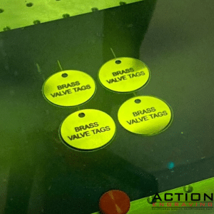 This photo shows brass valve tags inside the engraver while being engraved.